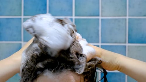 Woman Shampooing Dark Curly Hair in Shower