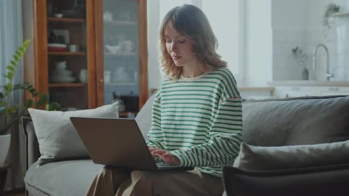 Woman Using Laptop on Sofa at Home