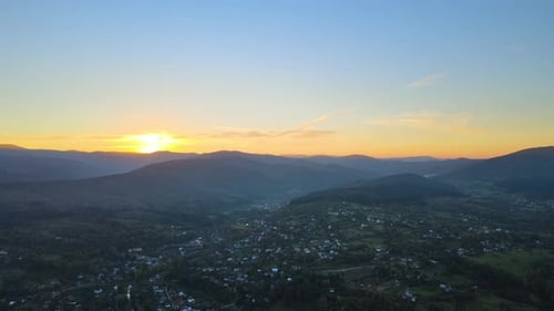 Aerial View of Amazing Scenery with Small Village Houses Between Foggy Dark Mountain Peaks Covered