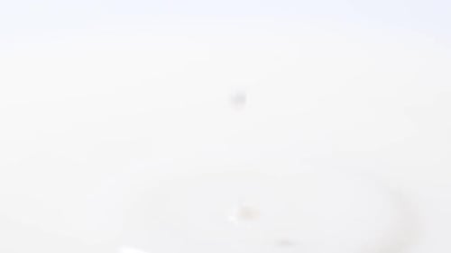 Macro Video Slow Motion of a Drop of White Milk Falling Into a Glass