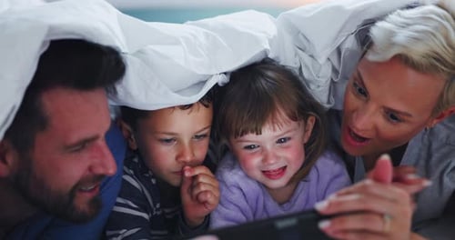 Family Together Under Blanket Watching Tablet
