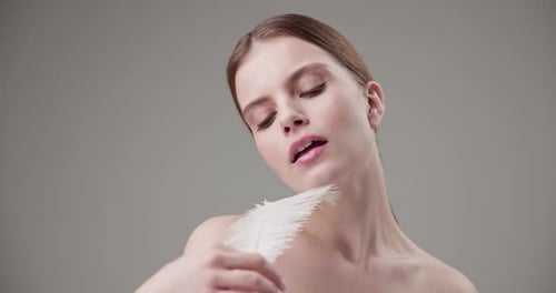 Elegant Woman Touches Face With White Feather