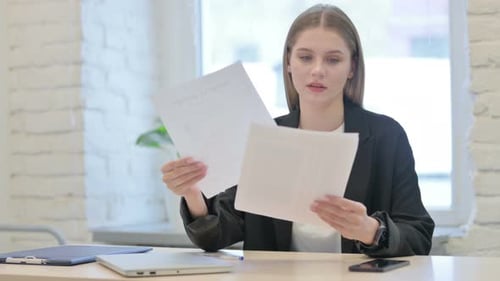 Businesswoman Celebrating Success while Reading Documents in Office