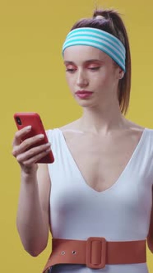 Stylish Woman Using Smartphone on Yellow Background