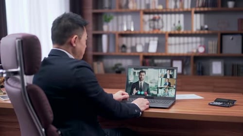Rear view asian businessman holds a business meeting looking at monitor laptop screen remote,