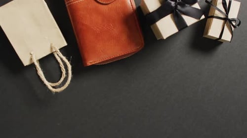 Lederhandtasche, Geschenktüte und Geschenkboxen mit schwarzen Bändern auf schwarzem Hintergrund mit Kopierraum