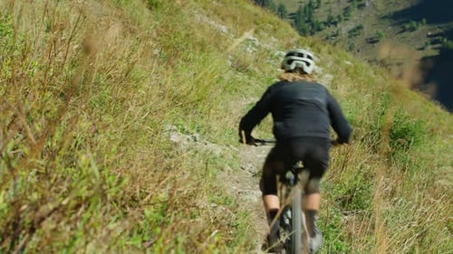 A cyclist rides down an alpine trail in autumn