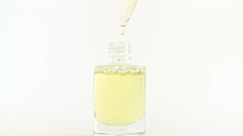Dropping Oil into Clear Glass Cosmetic Bottle