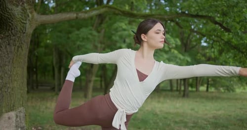 Young Beautiful Athletic Woman in Sportswear Doing Stretching and Warming Up in the Park Near a Tree