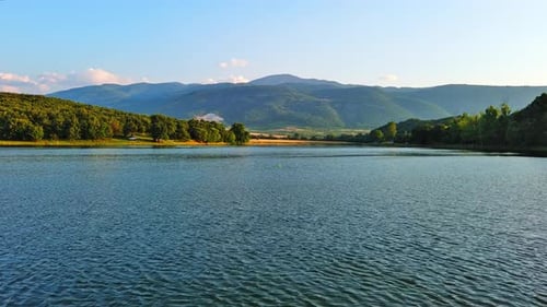 See mit klarem Wasser und Steinufer im Fichtenwald mit Tannen vor einem Tageshimmel