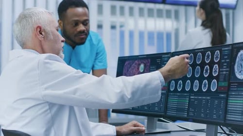 Medical Scientist and Surgeon Discussing CT / MRI Brain Scan Images on a Personal Computer in Labor