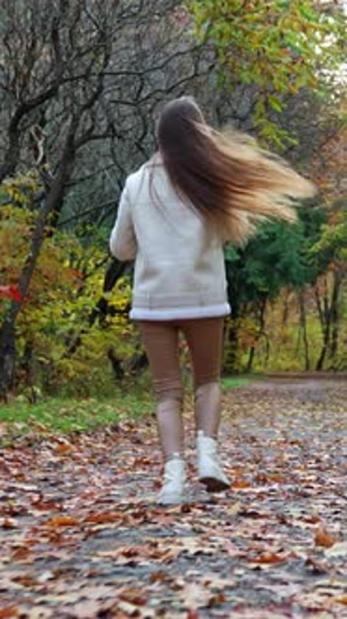 Outdoor playful young lady in autumn park. Stylish beautiful female lifestyle. Vertical video