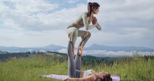 Two Women Practicing Acroyoga on Grassy Hillside