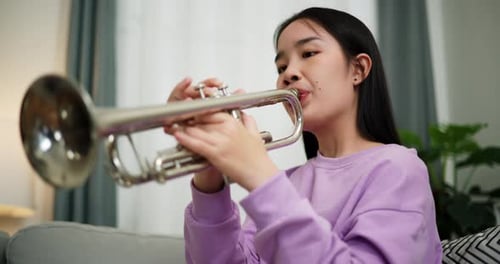 Young Woman Plays Silver Trumpet Indoors