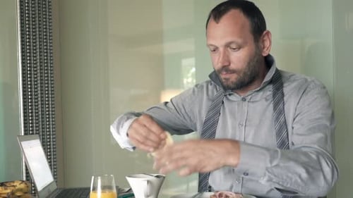 Man Prepares and Eats Sandwich at Desk