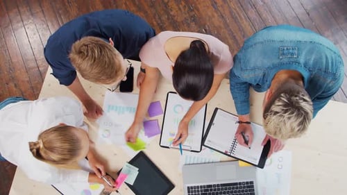 Team of Young Startupers is Working at the Table in the Office Discussing the Strategy and