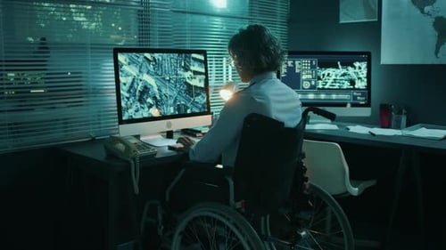 Person in Wheelchair Answers Phone at Computer Desk