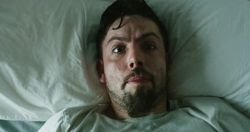 Man Lying in Bed Showing Signs of Distress