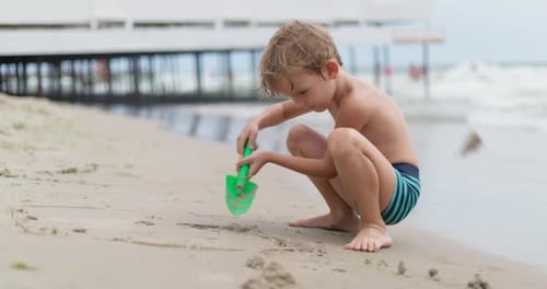 Young Boy Playing in Sand on Beach
