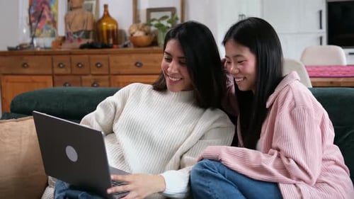 Happy asian friends watching videos on laptop computer