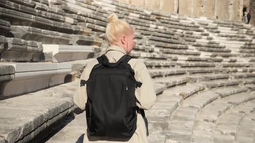 Woman Rides Up the Steps of an Ancient Amphitheater and Examines It