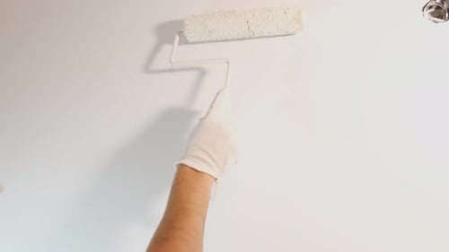Arm and Hand Painting a Wall White