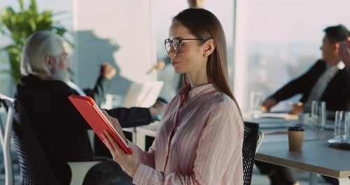 Smiling Businesswoman Using Tablet Device During Corporate Meeting