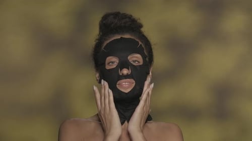 Woman Smoothing Black Facial Mask on Her Face
