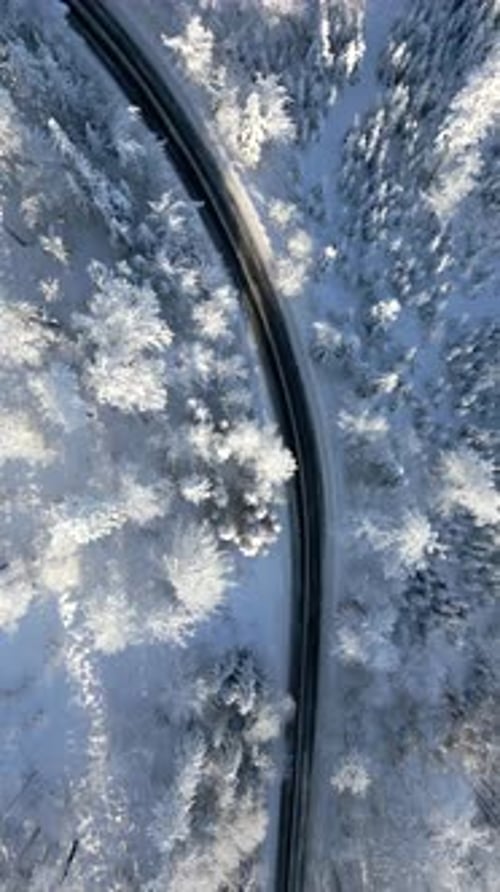 Aerial View of Scenic Road Winding Through Snowy Winter Mountain Forest