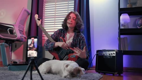 Young Adult with Guitar Records Video at Home