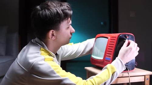 Young Man Adjusting Retro Red Television Set