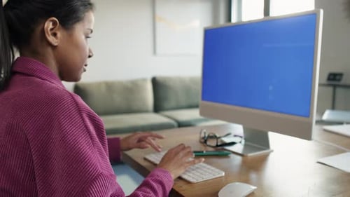 Side view of woman working on computer with blue screen. Shot with RED helium camera in 8K.