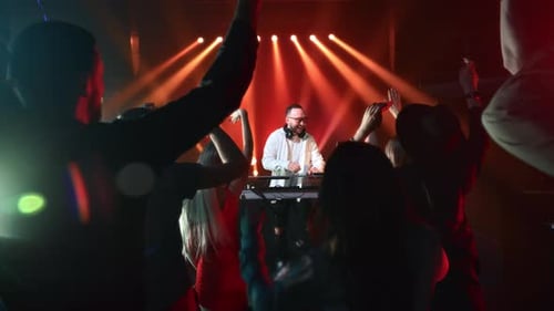 Artistic Man DJ Live Performance Party Illuminated Stage Crowded Dance Floor Dancing Fan Audience