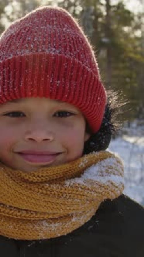 Vertikales Porträt eines glücklichen afroamerikanischen Jungen im Winterwald