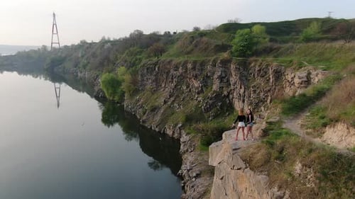 Two young ladies are stretching and posing on top of a rocky cliff, 4k