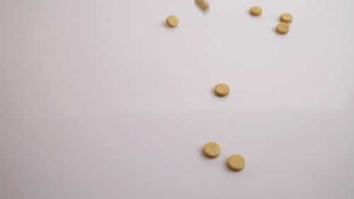 Painrelieving Yellow Pills Fall on the White Table