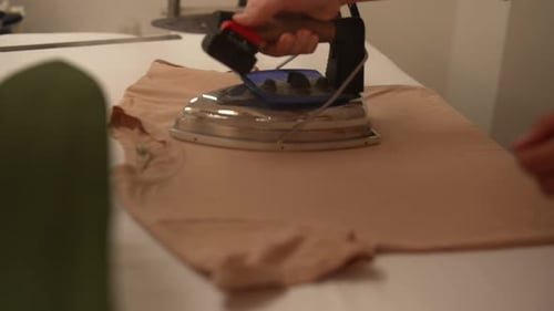 Closeup Hands of Tailor Ironing Beige Textile with Professional Iron in Workshop Precision and Care