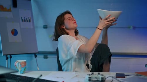 Young Slim Woman Holding Bowl with Water Leaking From Ceiling in Garage