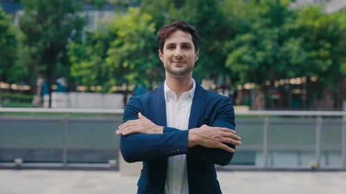 Portrait of the Handsome Young Guy Posing Outside with Crossing His Hands Dressed in a Blue Suit