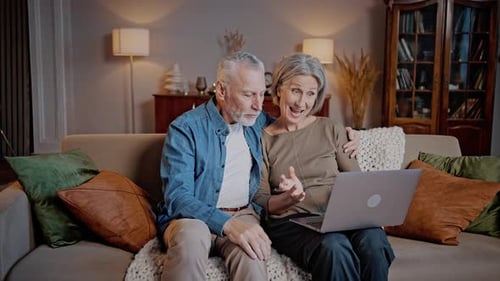 Senior Couple Video Chatting on Laptop at Home