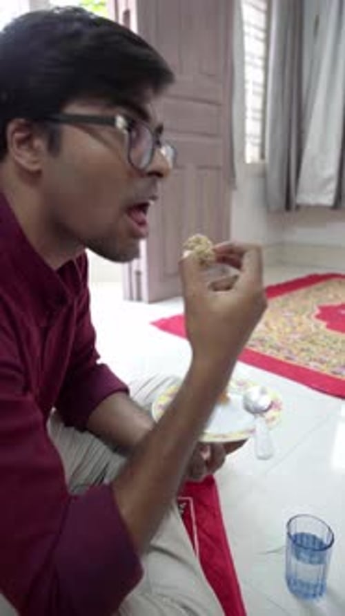 Joven celebrando el bhai dooj comiendo dulces tradicionales