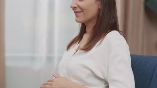 Smiling Pregnant Woman Sitting on Couch At Home
