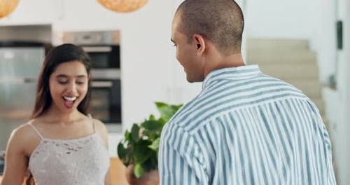 Man Surprises Woman With Flowers in Modern Kitchen