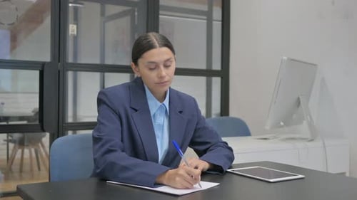 Hispanic Businesswoman Writing a Letter in Office
