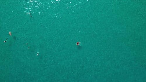 Aéreo, de cima para baixo, disparado por drone sobre pessoas nadando em mar azul-turquesa, dia ensolarado, em Tropea, Vibo Vale