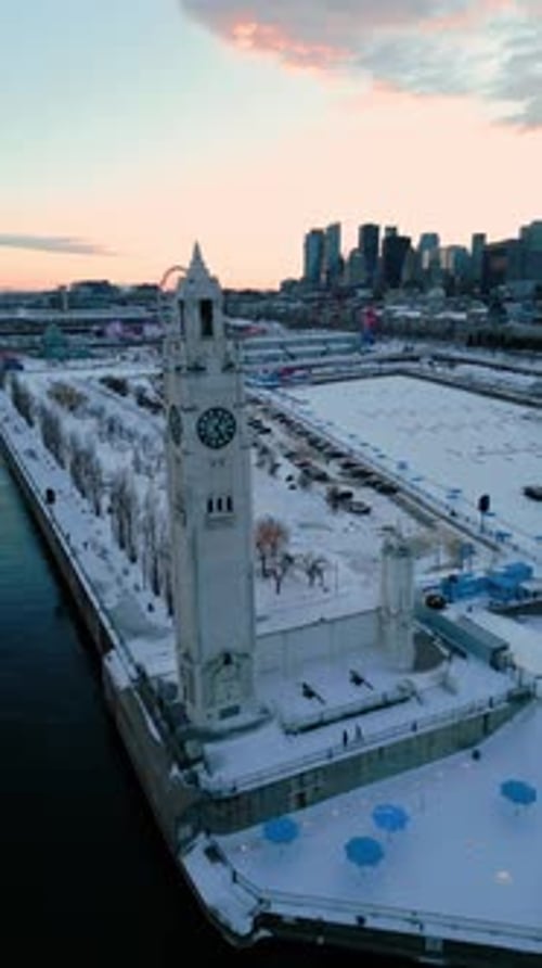 aerial vertical shot around Montreal clock tower in the old port during winter at sunset with th