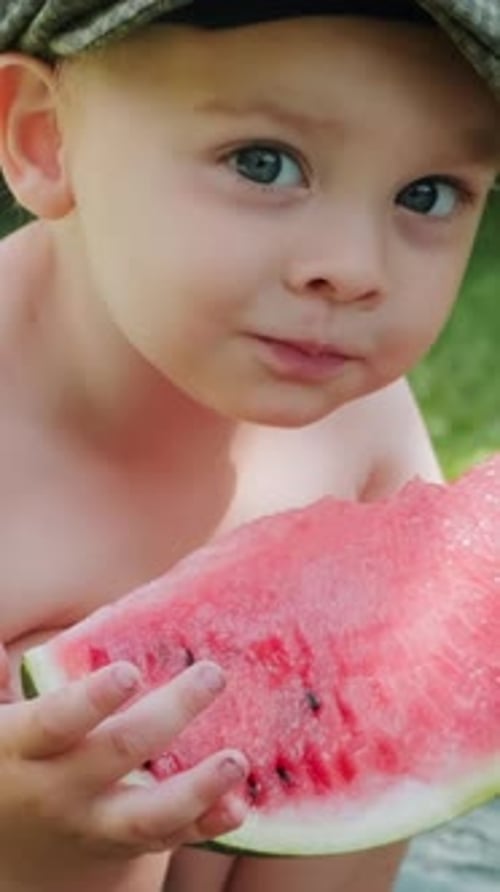 Child with Hat Eating Slice of Watermelon