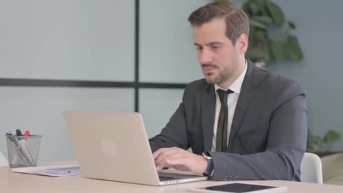 Man Working on Laptop in Modern Office