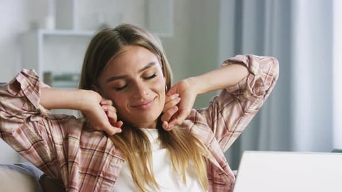Woman Relaxing and Stretching on Couch with Laptop