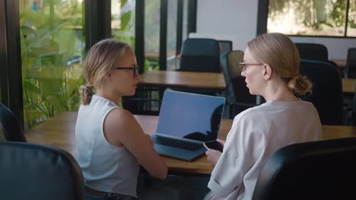 Two Young Ux Designers Collaborating in Modern Office Using Laptop and Smartphone to Discuss Ideas